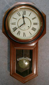 ANSONIA "REGULATOR A" IN A WALNUT CASE WITH BLACK BANDED BEZEL. NEW PAPER ROMAN DIAL.. CIRCA 1905-1910. — Antique Clocks Price Guide