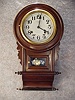 This A Japnanese Scroll Bottom Style School Clock In A Brown Adamantine Type Finish. Circa 1910-1920.