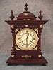German Bracket Clock By Junghans In A Walnut Veneered And Lindenwood Solids Softwood Case, With Brass Decorations Applied And 3 Finials On Top. Circa 1900-1910.