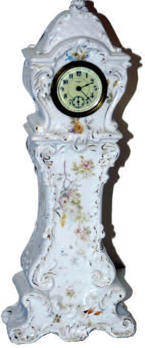 New Haven novelty porcelain clock, made to resemble a clock on a pedestal. Predominately white with a smattering of painted flowers and gold accent. — Antique Clocks Price Guide