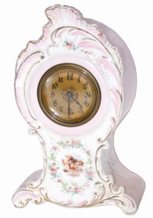 Miniature china clock, I would think it was kiln fired overseas as most all were. Principal colors are pinks, white, gold, and painted flowers on the front and sides. — Antique Clocks Price Guide
