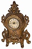 Warner metal novelty clock, 11" high, and in good condition. There are cupids below the dial, a flat glass, good hands and an unsigned dial.