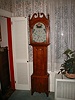 Smaller tall case clock with scrolled top and colorful dial.