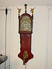 Friesian wall clock with painted dial and figures on bonnet.
