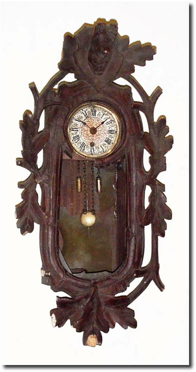 C.1930, German, Black Forest Mini Wall clock, in a carved hunting motif case of oak leaves and a deer head on top, distressed with several bits of carving broken away and missing; celluloid missing from door. — Antique Clocks Price Guide