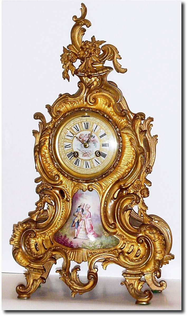 C.1900, French, a good Louis XVI style mantel clock with a lovely hand painted panel of a lady and gentleman in the park, and the porcelain dial with a winged cherub in the clouds and each numeral in a gold frame. — Antique Clocks Price Guide