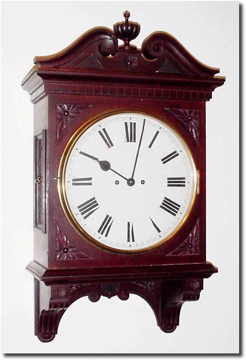 C.1890, English, 2-Fusee, Mahogany cased wall clock, in an attractive case with carved floral trim, carved base bracket, fretted and hinged side doors and a broken arch top with fluted center finial. — Antique Clocks Price Guide