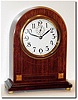 C.1920, English Alarm Clock in a mahogany round gothic case with satinwood and floral inlay, the base molding setting on 4 brass bun feet.