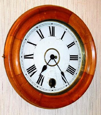 C.1900, New Haven "Eight Day Pendulum Time Clock" in a box case with turned wood bezel, the painted metal dial with a hole at 6 for attending the pendulum. — Antique Clocks Price Guide