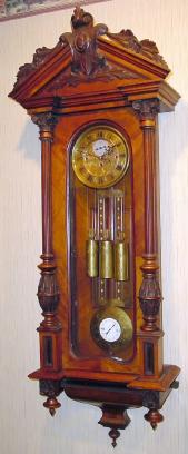 C.1880, Austrian, 3-Wt Grand Sonnerie, walnut cased wall clock with 3/4 columns and matching carved top, the dial center, pendulum and weights with matched scroll style engraving, the pendulum with grid iron accent, similarly engraved, and also with "R-A" center to bob, with steel pointer. — Antique Clocks Price Guide