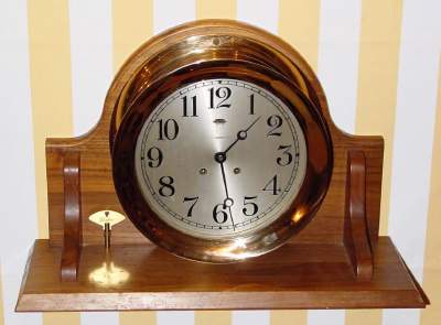 C.1923 Chelsea Clock Co., Boston. Mass., "Chelsea", 8-day ship's bell strike clock with the serial no. 158085 retailed by J. E. Caldwell and Co . (on dial) in a polished red brass case, 8 1/2" dial. (Now on a modern walnut stand) — Antique Clocks Price Guide