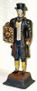  C.1975, German, Pot Metal CLOCK PEDDLER with working 1-day clock held in the front, an inanimate clock on his back, the 2 clock weights in his left hand. 