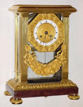 C.1840, French, Empire style 4-glass, the movement suspended between front 2 columns, glass around and on other 3 sides, and with a floral spray beneath. — Antique Clocks Price Guide