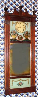 C.1820, Joseph Ives, "Patent Look-Glass" 8-day time/strike, 2-weight wall clock (short pendulum). This example is smaller than the standard size, which is closer to five feet tall. The case looks more like a large version of the reeded pilaster and scroll top case with a wood movement that was made by Ives and Lewis among others. — Antique Clocks Price Guide
