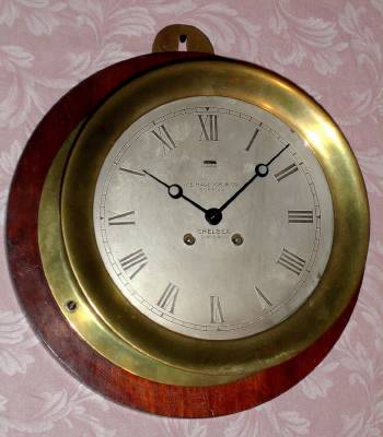C.1912, Chelsea Clock Co., 8.5" CHELSEA, Ship's Bell, 8-day, retailed by W. E. Hadlock and Co., Boston, serial 84708, model 104 with hinged bezel, mounted to a 12.5" dark pine board. — Antique Clocks Price Guide