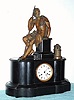 C.1890, French, Black Slate Figural clock, 8-day time and bell strike, with a patinated spelter statue of a seated and bare foot centurion with a container of papyrus records to his left. 