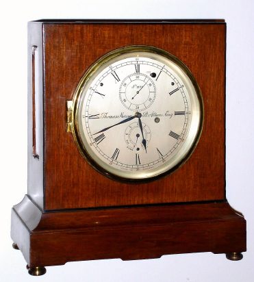 Mid 20th Century, Thomas Mercer, Ltd, St. Albans, England (1858-1954), No. 1131, 8-Day Chronometer table clock. Has a mahogany case with ebony stringing along the perimeter of all sides. Has a running "stop" at 1, bubble level on top of case, hinged brass bezel for winding, 11 jewel full chronometer detent platform is visible from top of case. There is info on the internet regarding Mercer, as well as in Ehrhardt's book 5, pages 103 and 129. — Antique Clocks Price Guide