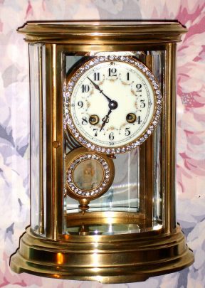 C.1900, French, Brass Cased, OVAL CRYSTAL regulator, 8-day time and gong strike, with a fancy brilliant studded portrait pendulum and matching bezel, the dial with floral polychrome decorations. — Antique Clocks Price Guide