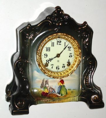 C.1904, Ansonia Royal Bonn, LA CANNES, porcelain china clock, 8-day time and gong strike, this version with 3 hand painted Dutch ladies mending nets at the shore, and boats in the distance. — Antique Clocks Price Guide