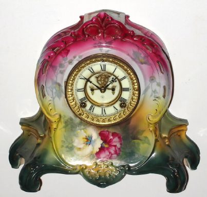 C.1904, Ansonia Clock Co., LA RIVIERE, Royal Bonn porcelain clock with open escapement dial, in a tri-color case, dark rose at top, next yellow and bottom dark green, and with brilliant floral decorations. — Antique Clocks Price Guide