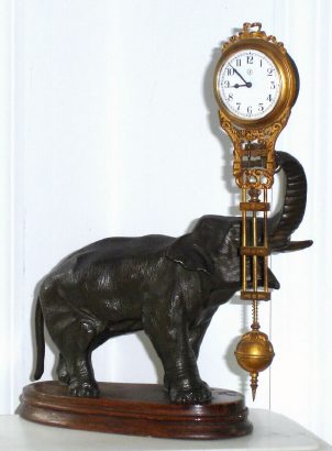 C.1910, German, Junghans, ELEPHANT,  patinated spelter mysterious swinging timepiece, 8-day, on a shaped wooden base with molded edge. — Antique Clocks Price Guide
