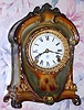 C.1910, Ansonia, Royal Bonn LA CRUZ, 8-day time and gong strike porcelain mantel clock, in New Art colors of very dark green accents of pastel rainbow colors and other highlights, and solid porcelain dial. 