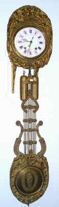 C.1860, French Morbier, 8-day time and bell strike w/ calendar, Comptoise wall clock with brass repousse dial surround with flower/basket theme, and with matching lyre pendulum, and with a sturdy purpose made wall mount. — Antique Clocks Price Guide