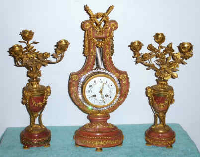 C.1880, French, 3-Piece Lyre Set, Brilliants swing from side to side, part of compound pendulum, in a rose colored marble case with ormolu trim. — Antique Clocks Price Guide