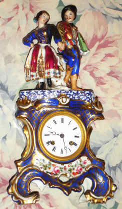 C.1850, French, Porcelain Mantel clock, two piece, with costumed lovers on top, the base color blue cobalt accented with gold highlights and floral displays. The silk thread bell strike movement with countwheel, 8-day. — Antique Clocks Price Guide