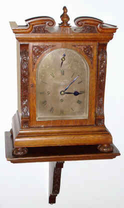 C.1900, English, J. W. Benson, London, 3-fusee, Westminster chime on large flat wire gongs, with the hours struck on a large cathedral gong, with a silvered brass dial with foliate engraving in the arch and spandrel areas, and with F/S adjust in the arch, plus original wall bracket. — Antique Clocks Price Guide