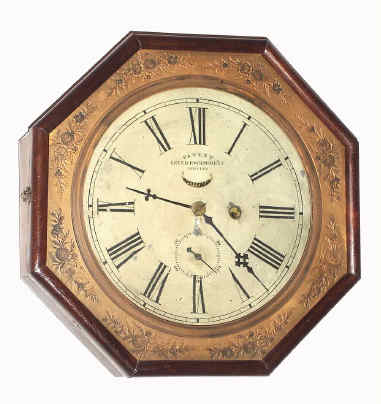 C.1865, Waterbury Clock Co., Octagon Lever, 8-day timepiece with Patent Jeweled Escapement, in a rosewood veneered case with an embossed brass dial surround. 8 bezel segments are solid rosewood. — Antique Clocks Price Guide