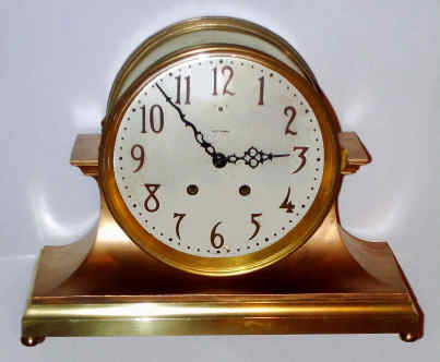 C.1913, Seth Thomas Clock Co., "COLOSSAL", metal cased mantel clock, same design as the Celtic, only larger. Base is cast bronze and the cylinder, bezel and rear cover are brass, and the outer body is cast white metal, bronzed. Silvered dial with raised bronze numerals. — Antique Clocks Price Guide