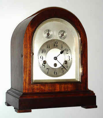 C.1910, German, Junghans, Wurtemberg, Westminster chime mantel clock in a round gothic mahogany case, button latch door and beveled glass front, arched silvered dial with subsidiary rings for F/S and Chime/Silent. — Antique Clocks Price Guide