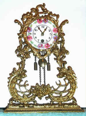C.1930 German, 30-hour porcelain face, key wind, pendulum timepiece mounted in a brass plated spelter filigree case. — Antique Clocks Price Guide