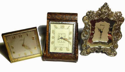 Lot of Three Travel Clocks- (3); Angelus contract for "Tiffany and Co." 8-day 15J in gilt case including original outer leather travel case 2.75"H, a Jaeger 8-day alarm in snakeskin folding travel case 4.25"H, and a Cyma contract for Gorham in silver frame with collapsible stand 4.75"H. — Antique Clocks Price Guide