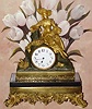 C.1900, French, Ormolu and Marble, figural clock, the Fruit Lady, in Victorian dress and hat, attending a basket of fruit and blossoms, with a bouquet in her left hand, time only movement, 8-day, rear wind and set.