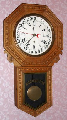 New Haven Clock Co, New Haven Conn, "BANK" calendar model, long drop embossed oak school clock, 8 day time mvt in oak case with 12" dial, spring driven. C. 1910. — Antique Clocks Price Guide