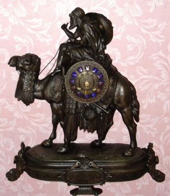 French figural white metal mantel clock, Arabic motif depicting Bedouin mounted on camel. Dial has applied gilt Roman numerals on blue enamel plaques and base has plaque with Arabic inscription, time and strike on bell 8 day spring driven mvt. C. 1870. — Antique Clocks Price Guide