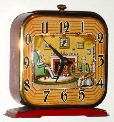 Lux Clock Mfg, Waterbury, Conn, SPINNING WHEEL novelty alarm, showing grandpa before the fire smoking his pipe and grandma sitting at her spinning wheel which revolves a bit with each tick. C.1935. — Antique Clocks Price Guide