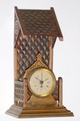 Parker Clock Co, unusual 1-day desk calendar in a novelty case of brass, the clock setting in a small roofed alcove. This is a rear wind, rear set clock and retains its special key for doing both. C.1895. — Antique Clocks Price Guide