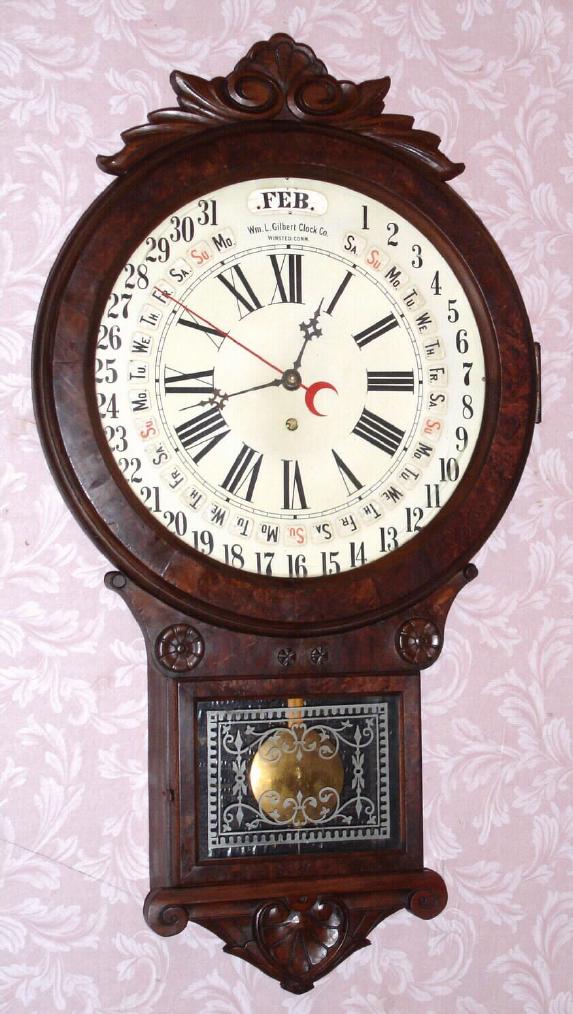 Wm. L. Gilbert, OFFICE DROP CALENDAR, C.1881, with Maranville type rotating disc simple calendar with month and days of the week, in a walnut case with carved trim and burled accents. Note Gilbert used paper discs, moved by a pointer, to evade the Maranville patent. — Antique Clocks Price Guide