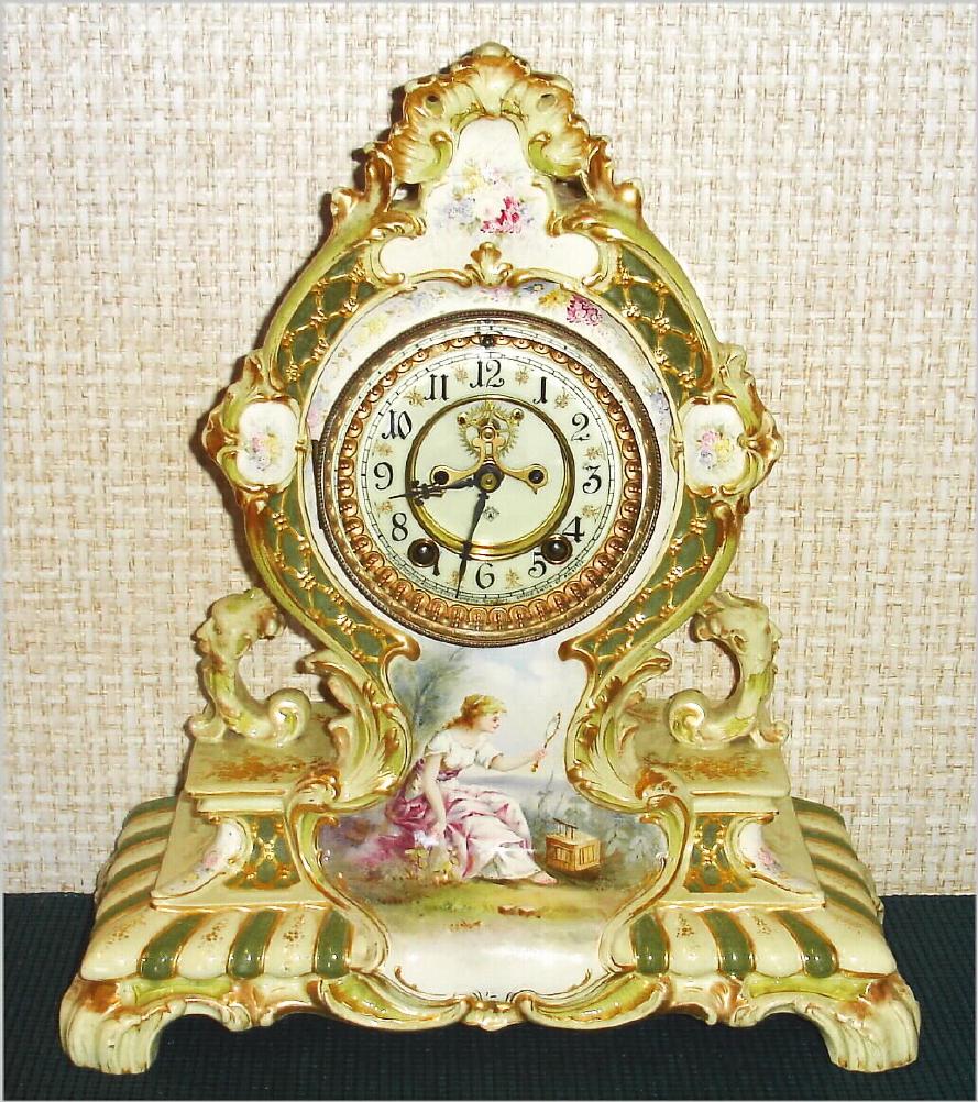 Ansonia Clock Co., C.1910, Royal Bonn, "LA CERDA" porcelain china cased clock, with 8-day, gong strike mov't with open escapement on porcelain dial, with a hand painted portrait of a lady setting in a garden looking in her hand mirror. — Antique Clocks Price Guide