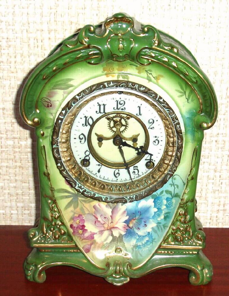 Ansonia Clock Co., C.1914, Royal Bonn, "LA CRUZ" porcelain china cased clock, with 8-day, gong strike mov't with open escapement on porcelain dial, in a medium green case with multi colored flowers to the case front and sides. — Antique Clocks Price Guide