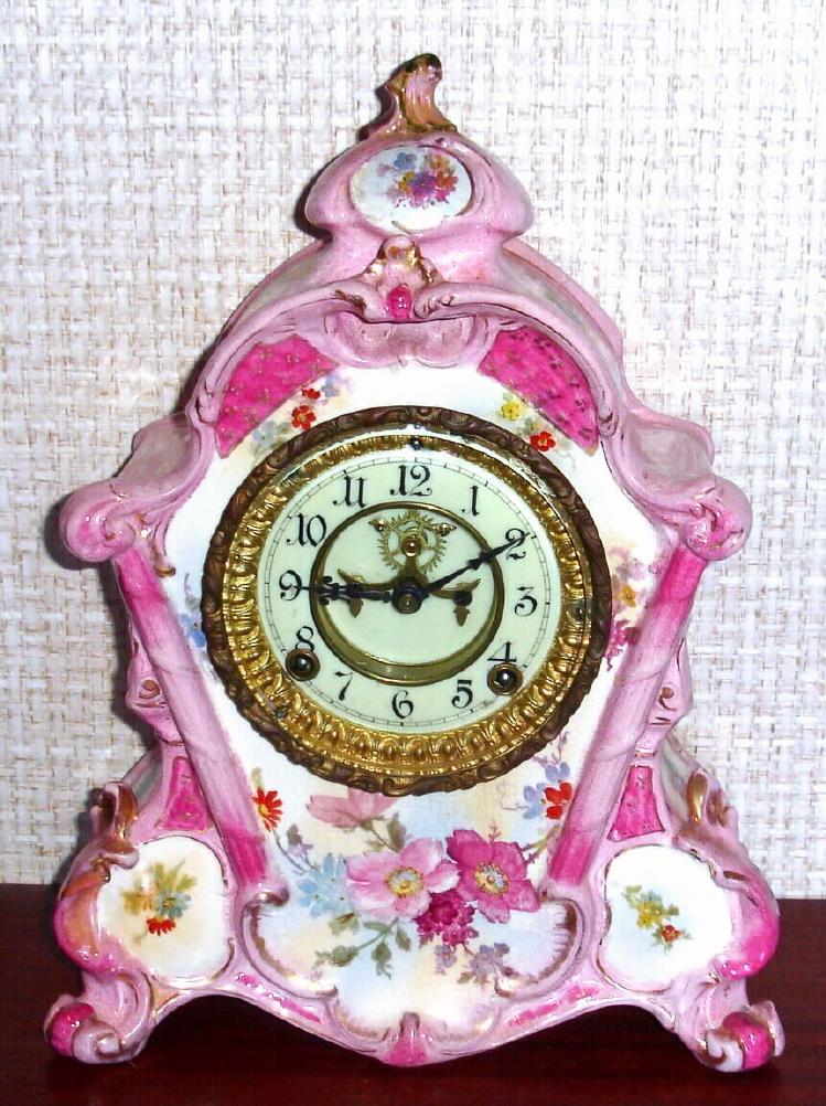 Ansonia Clock Co., C.1895, Royal Bonn, "No. 502" porcelain china cased clock, with 8-day, gong strike mov't, open escapement in the center of the 2-piece porcelain dial, and the case a wonderful pink color with matching floral accents and gold highlights. — Antique Clocks Price Guide