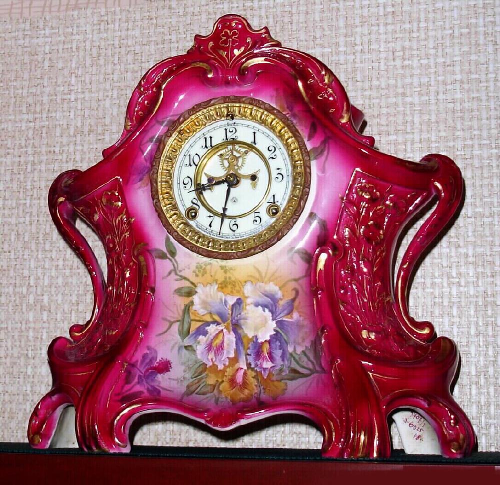 Ansonia Clock Co., Royal Bonn, "LA LAYON", large porcelain clock in the French style, C.1905, with open escapement on the porcelain dial. Color is dark red rose with Iris decorations and profuse gold highlights. — Antique Clocks Price Guide