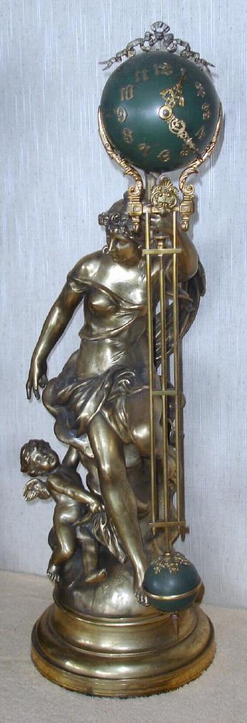 Ansonia Clock Co. New York, C.1900, "FORTUNA", swinging arm timepiece, 8-day, the movement contained within the ball at top, the 25.5" clock arm swings from side to side without apparent impulse. The goddess Fortuna is setting with a cherub playing at her side, holding the clock aloft. — Antique Clocks Price Guide