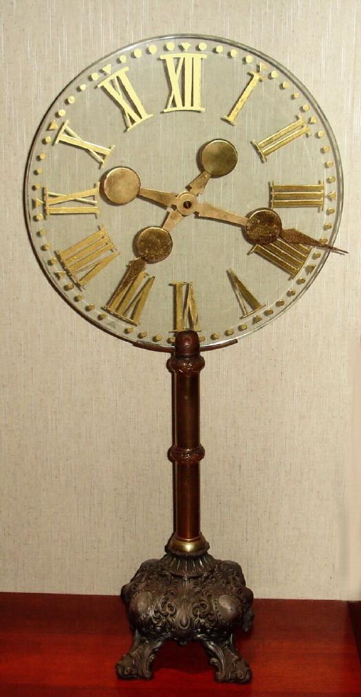 French, Early 20th Century, MYSTERIOUS timepiece, two gilt hands attached to a large glass dial. A Swiss watch movement in each hand, one geared to turn once an hour, the other designed to turn once in 12 hours. See detail fotos of movement and also pivoted counter balance on opposite side of hand. — Antique Clocks Price Guide