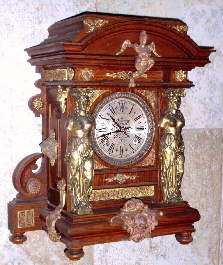 Ansonia Clock Co., New York, C.1894 "SENATOR", antique oak cased mantle clock with brass trimmings. Features full figured female columns on either side of the dial with other large and impressive brass plated bits. 8-day, time and gong striking. — Antique Clocks Price Guide