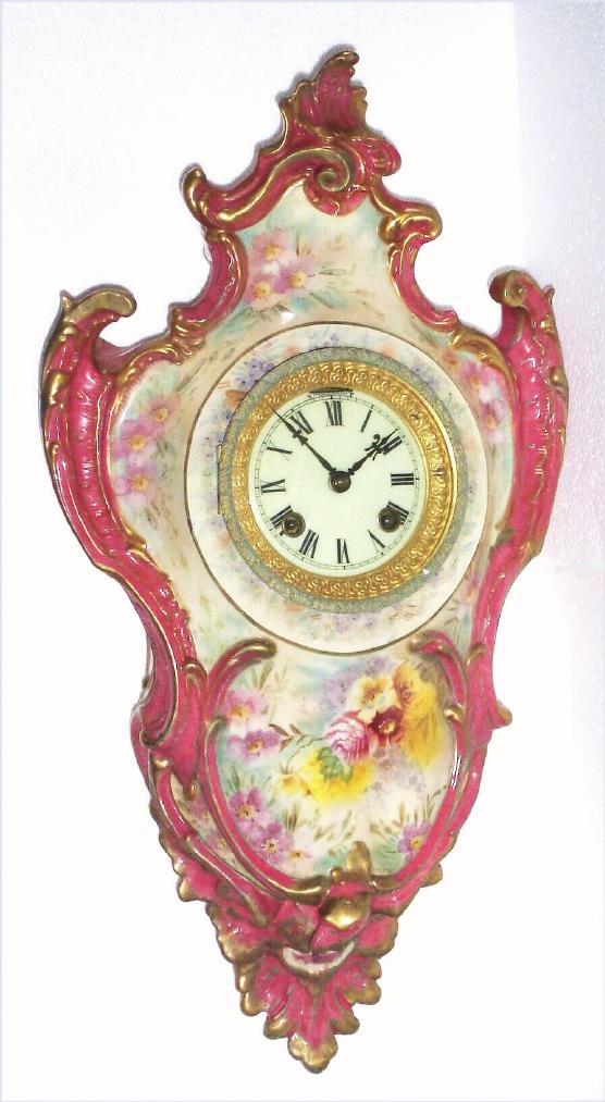 Ansonia Clock Co., C.1906, Royal Bonn, "PORCELAIN HANGING No. 3" china cased wall clock, with flower pattern to case, bell strike balance wheel, 8-day mov't. Color is a lt brownish rose or mauve. — Antique Clocks Price Guide