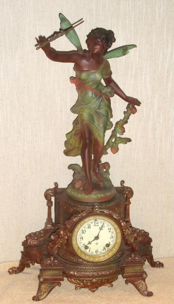 Ansonia Clock Co., New York, C.1880, "OLYMPIA and CHLORUS" figural clock, with fancy creamy porcelain dial with red accents, the statue and base in new art tints. — Antique Clocks Price Guide